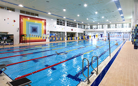 실내수영장 내부 측면에서 찍은 사진으로 수영장 레일마다 수영하고있는 사람들의 모습