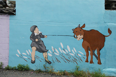 어린 학생이 소를 묶은 줄을 힘껏 당기고 있는 모습이 그려져 있는 벽화