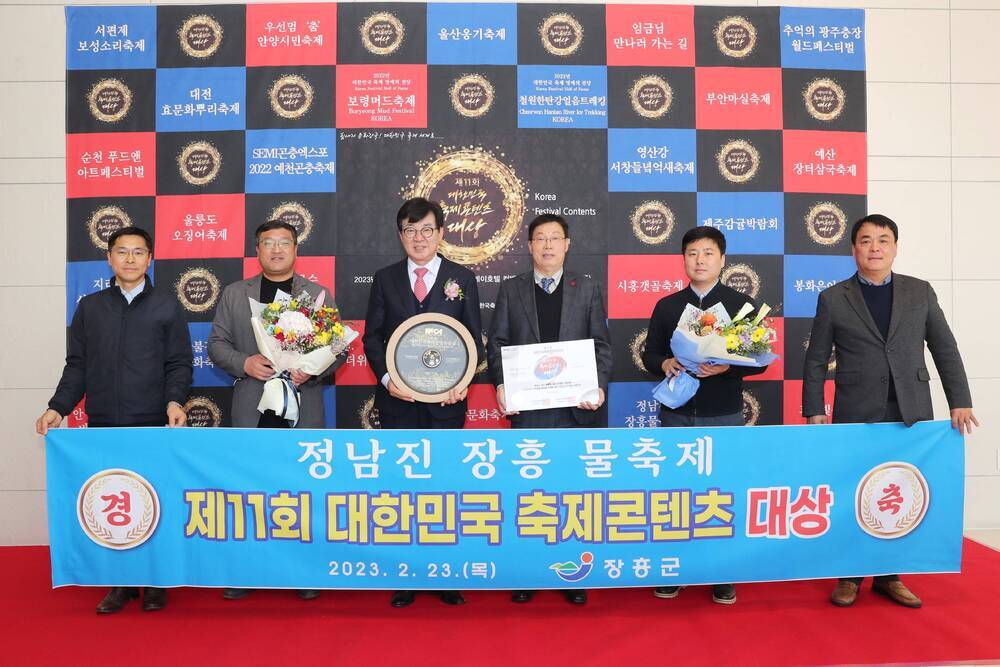 플래카드-경축 정남진 장흥물축제 제11회 대한민국축제콘텐츠 대상 2023.2.23(목) 장흥군, 상패와 상장, 꽃다발을 들고 있는 장흥군수와 장흥군 공무원들